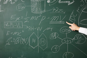 黒板に書かれた数式に指を指す