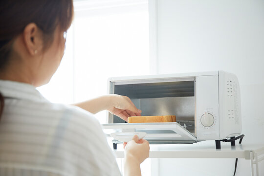 トースターでパンを焼く女性