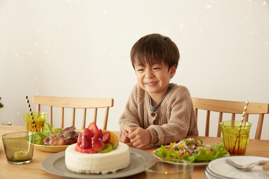 パーティーの準備がされているテーブルで嬉しそうに笑う男の子