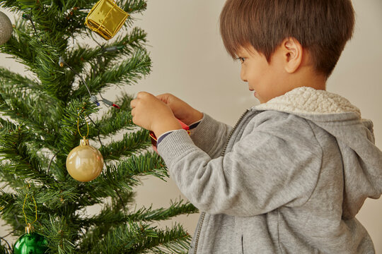 クリスマスツリーの飾り付けをする男の子