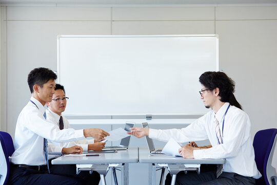 対面に座り書類を渡している社員の様子