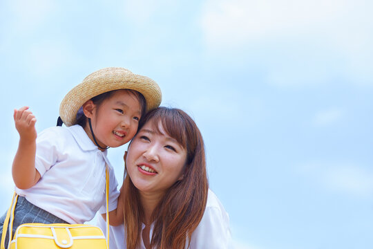 青空を背景に頬を摺り寄せて笑う母と子