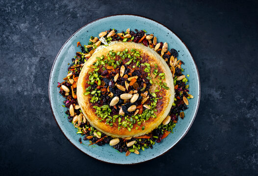 Traditional Persian tahdig jeweled javaher polow bride basmati rice with dried fruits and berries served as top view on a Nordic design plate with copy space