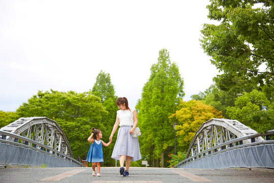 公園内の歩道橋の上を散歩するお母さんと女の子