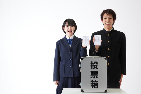 投票箱の上で投票用紙を持つ学生