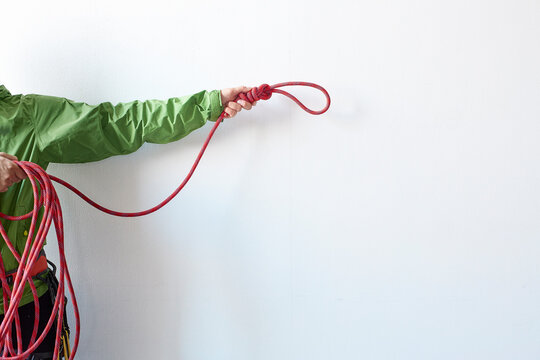 白い壁の前で結び目とまとまったをロープを持つ登山者