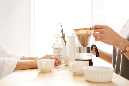 キッチンカウンターでコーヒーを注ぐ男女の手元