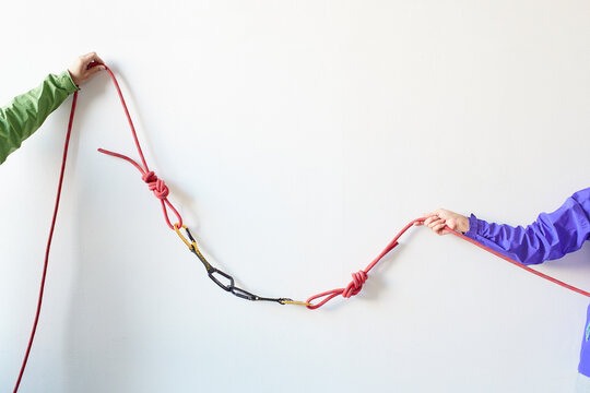 白い壁の前でカラビナがかかったロープを引っ張る２人の登山者