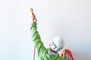 白い壁の前でロープを持ちカラビナを引っ掛けようとする登山者