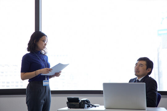 書類を渡そうとする女性と嫌な顔をする上司