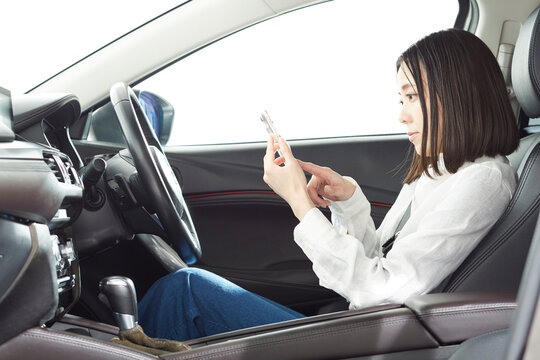 運転席でスマートフォンを操作する女性