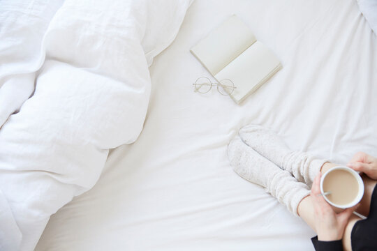 ベッドの上に座ってカップを持つ女性の俯瞰