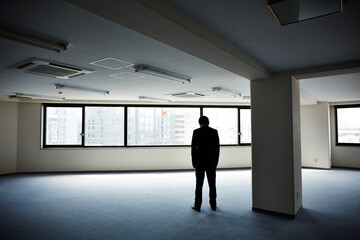 何もないオフィスで下を向き立ちすくむ男性
