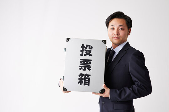 投票箱を持つスーツを着た男性