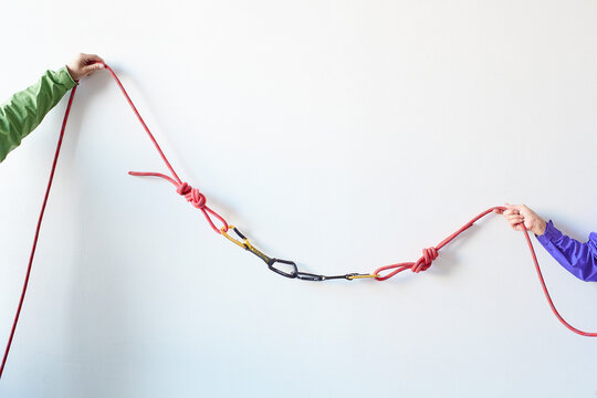 白い壁の前でカラビナがかかったロープを引っ張る２人の登山者