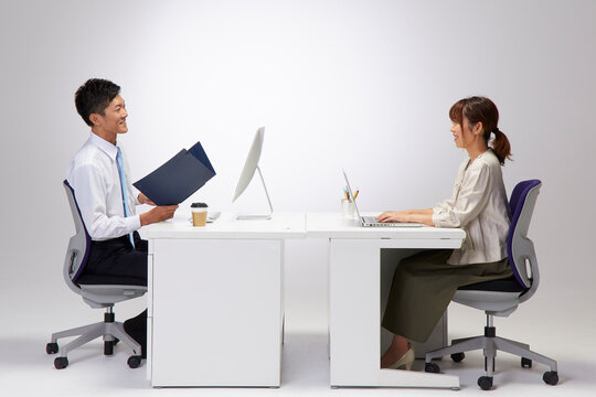 向かい合わせのデスクで仕事をする男女