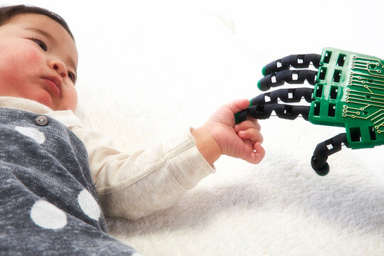 ロボットの手を握る赤ちゃん