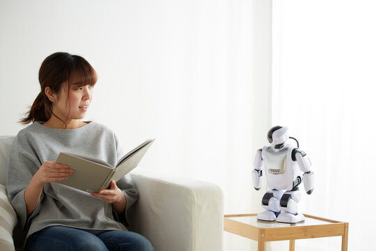 本を読みながらロボットと会話する女性