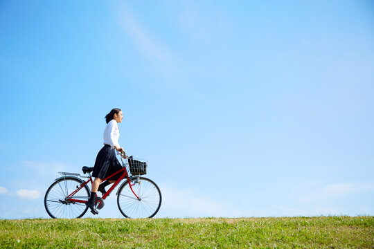 河川敷を自転車で走る女子高生