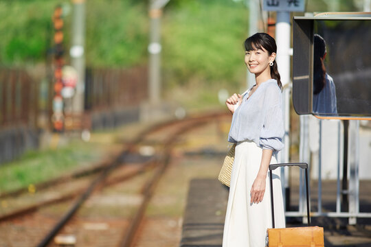 駅のホームで電車を待つ女性