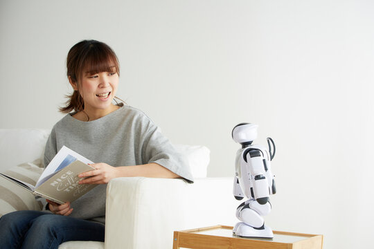 本を読みながらロボットと会話する女性
