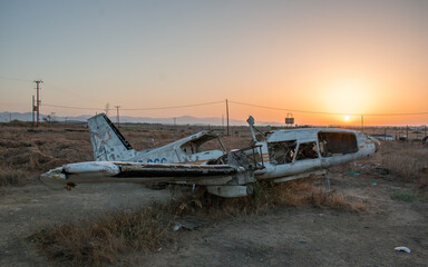 Beautiful image of an old broken airplane in an isolated area with a mesmerizing sunset background