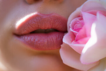 Close up photo of woman's lips with natural make up. Beautiful woman lips with rose.