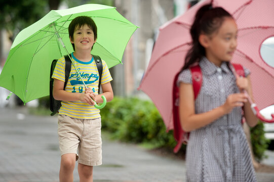 雨天の登下校で傘をさした小学生子供男女