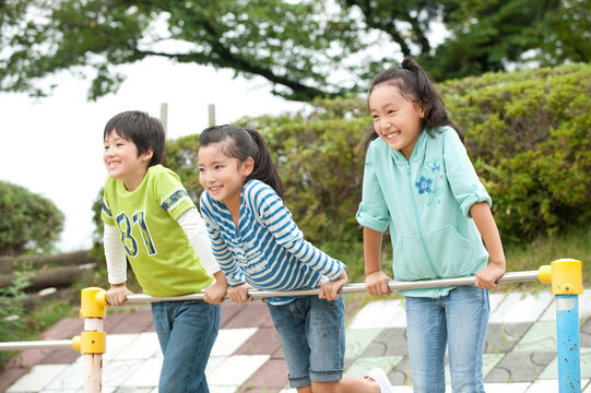 公園で鉄棒をする子供男女３人
