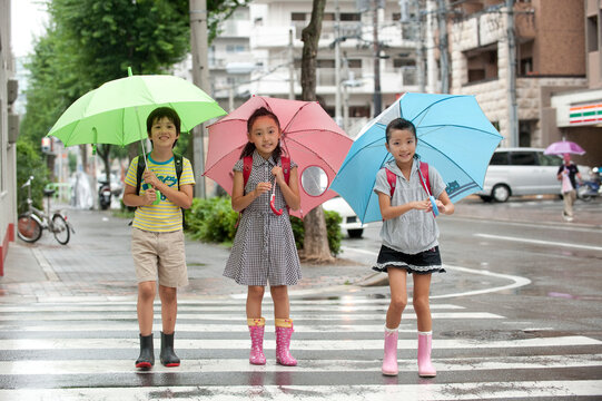 雨天の登下校で傘をさした小学生子供男女3人 ,名古屋市