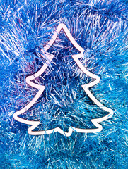 Christmas tree white frame on sparkling tinsel decoration in icy blue and silver colour with purple poral light. Creative copy space. Winter background. New Year or Christmas concept. Minimal layout.