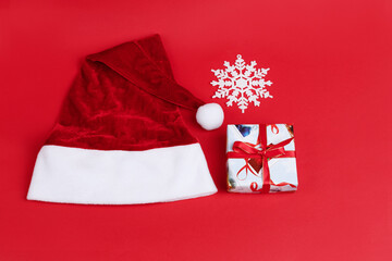 Santa Claus hat and a gift on a red New Year's background. Christmas gift