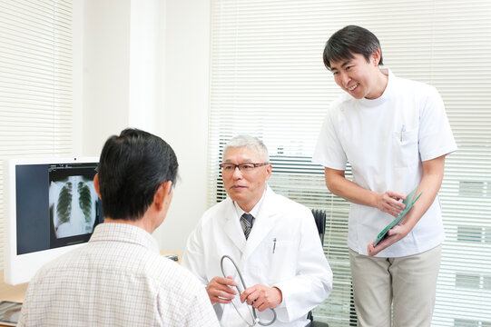 老人患者を診察する中高年の医師と男性看護師