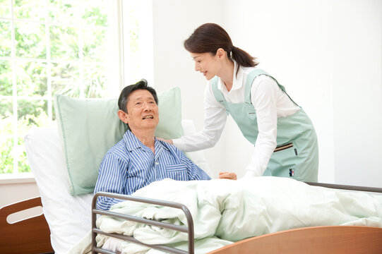 介護ベッドの老人と介護ヘルパー