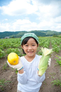 畑で収穫した野菜を持つ女の子