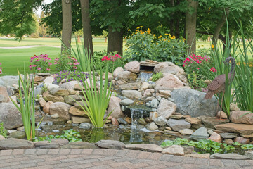 Mature landscaping around a backyard water feature created by the homeowner