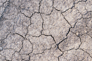 Cracked earth texture of ground, broken and rough surface gray mud clay soil in summer season, cracked ground floor on arid drought environment