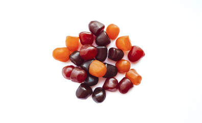Close-up texture of red, orange and purple multivitamin gummies on white background. Healthy lifestyle concept