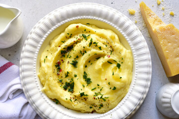 Mashed potato with parmesan cheese and herb in a white bowl . Top view with copy space.