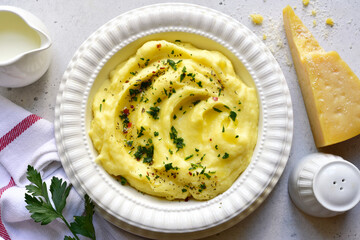 Mashed potato with parmesan cheese and herb in a white bowl . Top view with copy space.
