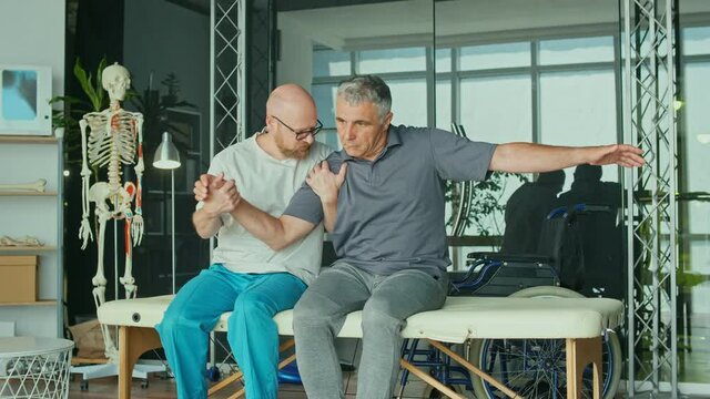 A Sick Man With a Brain Stroke Undergoes a Rehabilitation Program with a Physiotherapist in a Modern Clinic. Incapacity for Work, Limited Movement, Paralysis. Elderly Health Support Concept.