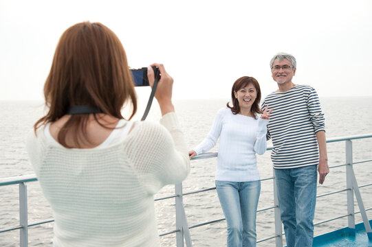 フェリーのデッキで写真を撮る三人家族