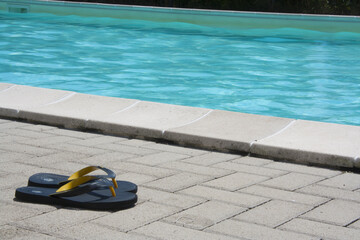 Flip-flops in front of the pool on a sunny day