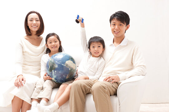 地球儀と人工衛星模型で遊ぶ子供の四人家族