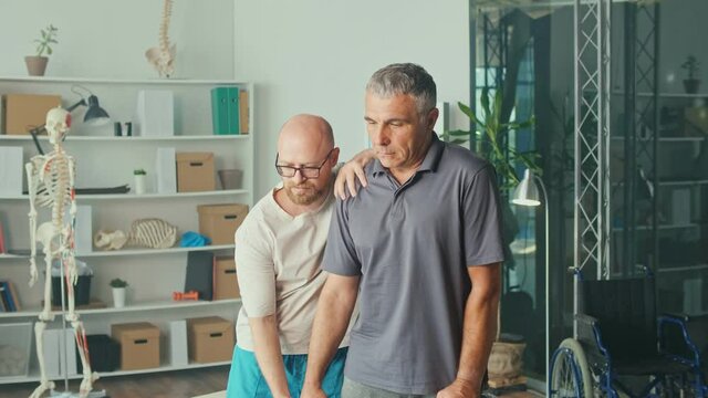 Senior Man a Brain Stroke Doing Dumbbell Exercises as Part of a Rehabilitation Program with a Physiotherapist in a Modern Clinic. Paralysis of the Facial Nerve, Limited Movement. Rehabilitation.