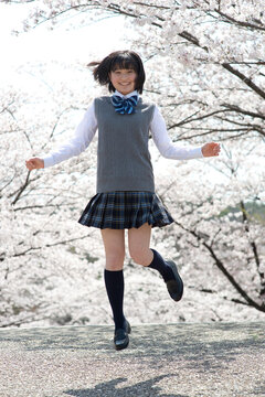 桜とジャンプする女子高生