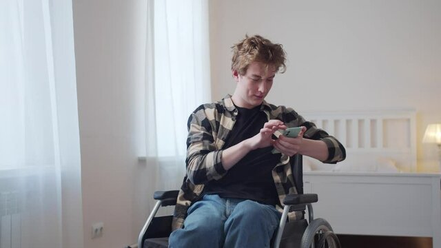 A disabled man is sitting in his wheelchair and looking through the Internet 