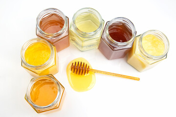 spoon with fresh honey and jars with different types of honey on a white background. organic vitamin food