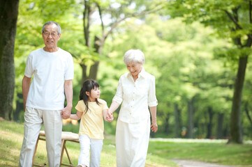公園を孫と散歩するシニア夫婦