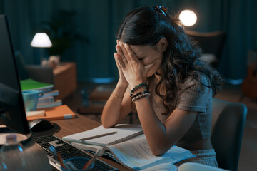 Depressed stressed woman sitting at desk - obrazy, fototapety, plakaty